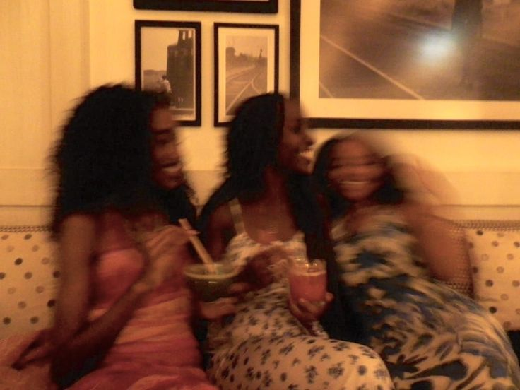 Three young women laughing together on a sofa